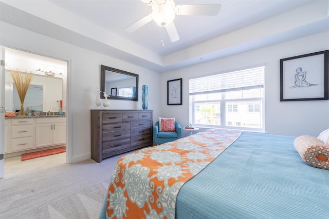 bedroom with light carpet, ensuite bath, a sink, and a ceiling fan