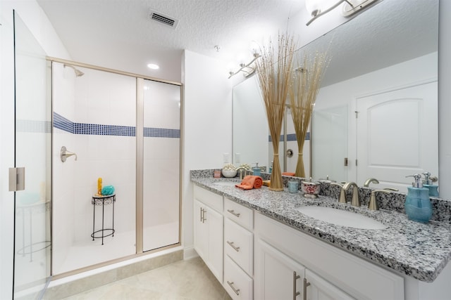 bathroom featuring a shower stall, a textured ceiling, vanity, tile patterned flooring, and visible vents