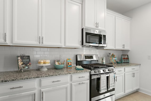 kitchen with light stone counters, decorative backsplash, white cabinets, and stainless steel appliances