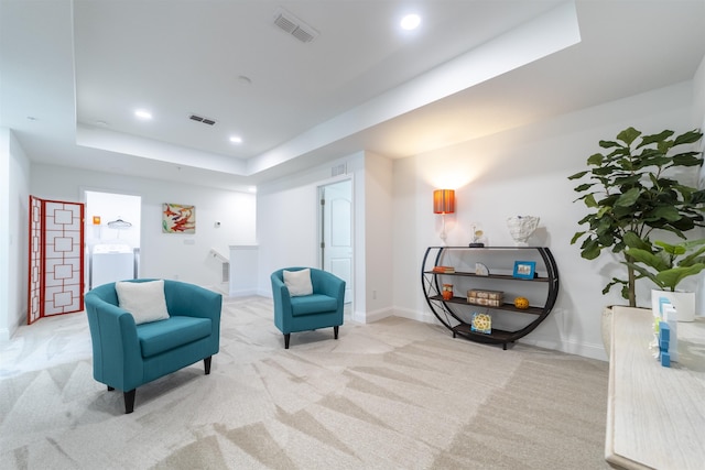 sitting room featuring a tray ceiling, visible vents, washer / dryer, and carpet floors