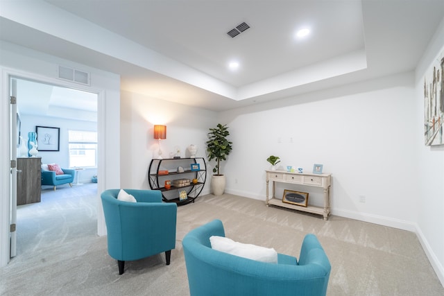 sitting room with visible vents, baseboards, and light carpet