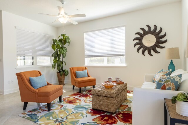 living area featuring ceiling fan, baseboards, and light tile patterned flooring