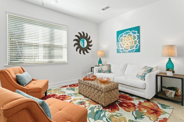 living area with visible vents, baseboards, and ceiling fan