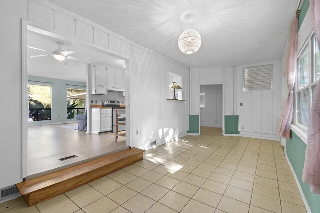 tiled foyer entrance with ceiling fan with notable chandelier