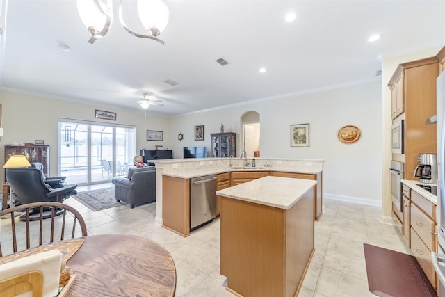 kitchen featuring arched walkways, a kitchen island, open floor plan, stainless steel appliances, and a sink