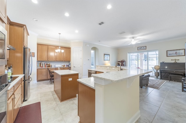 kitchen featuring a spacious island, a sink, visible vents, ornamental molding, and appliances with stainless steel finishes