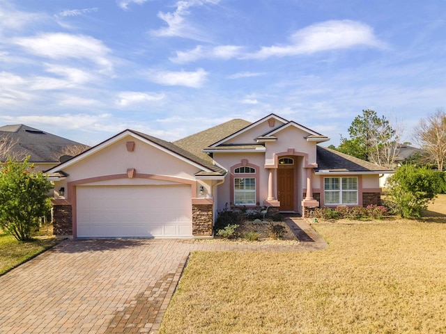 ranch-style home featuring a garage, stone siding, decorative driveway, and stucco siding