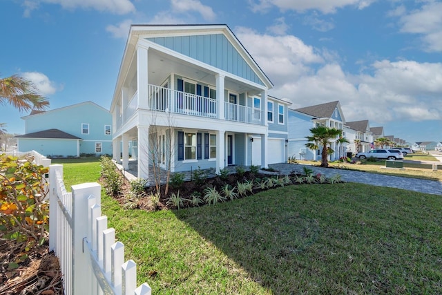 view of front of home featuring board and batten siding, fence, a garage, a balcony, and driveway