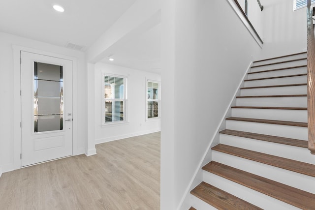 entryway with visible vents, baseboards, light wood finished floors, recessed lighting, and stairs