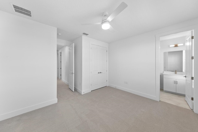 unfurnished bedroom with a sink, visible vents, baseboards, and light colored carpet