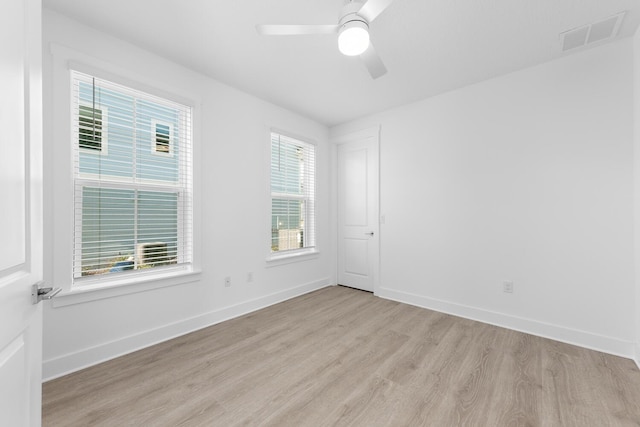 empty room featuring visible vents, a ceiling fan, baseboards, and wood finished floors