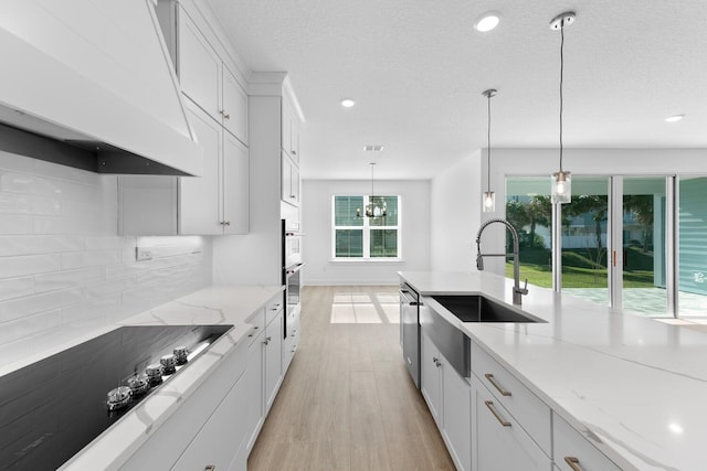 kitchen with decorative backsplash, white cabinets, light wood finished floors, black electric cooktop, and custom exhaust hood