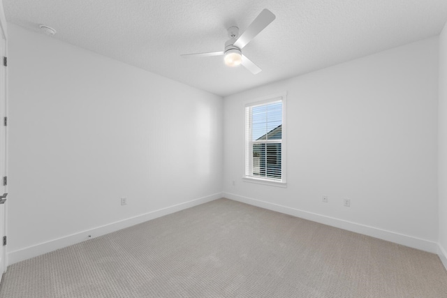 spare room featuring baseboards, light carpet, a textured ceiling, and a ceiling fan