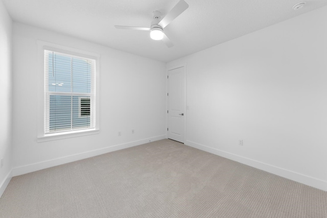 spare room with baseboards, light colored carpet, and ceiling fan