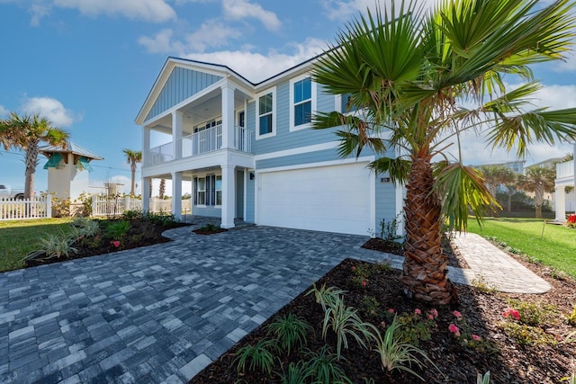 view of front of house with a balcony, fence, a garage, decorative driveway, and board and batten siding