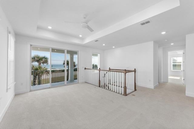 unfurnished room featuring visible vents, a tray ceiling, light carpet, recessed lighting, and a ceiling fan