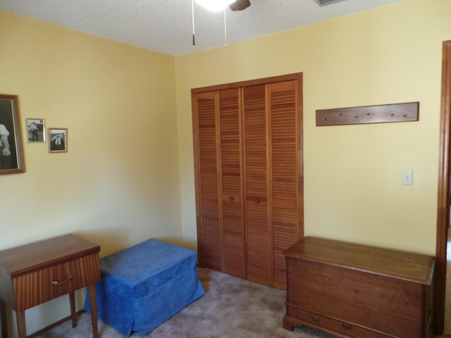 bedroom with a textured ceiling, carpet flooring, a closet, and ceiling fan