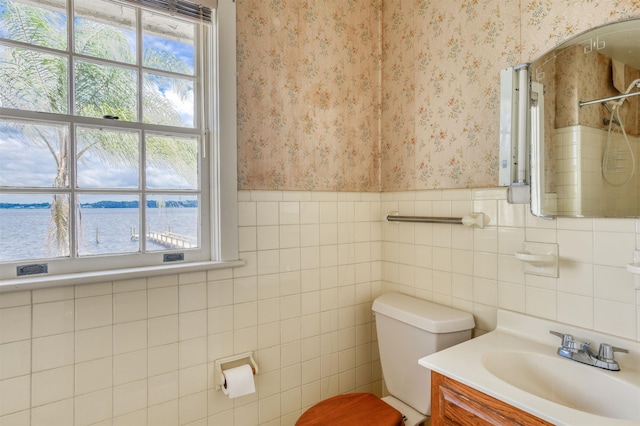 bathroom with vanity, a water view, tile walls, and toilet