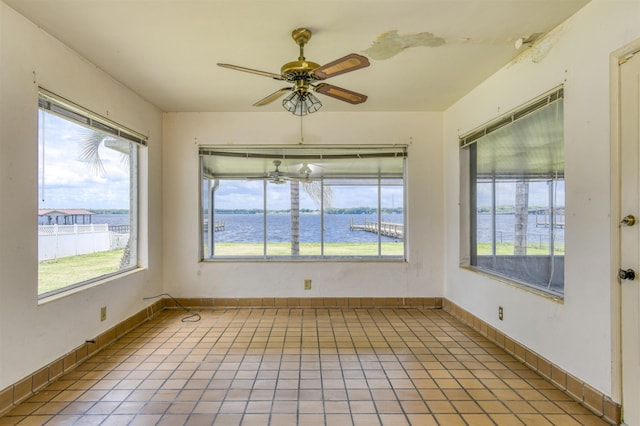 unfurnished sunroom featuring a water view and ceiling fan