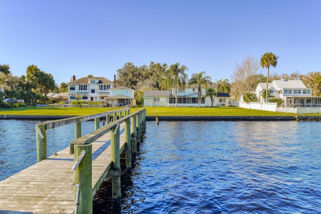 view of dock with a lawn and a water view