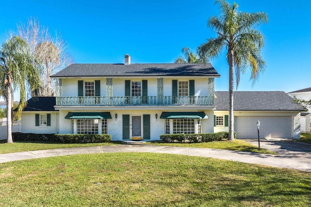 view of front of home featuring a garage, a balcony, and a front lawn