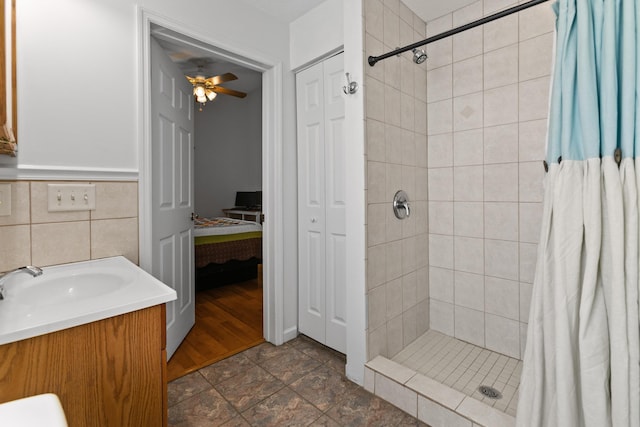 bathroom featuring a shower with shower curtain, tile patterned floors, vanity, ceiling fan, and tile walls