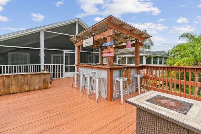 deck with a sunroom, a bar, and an outdoor fire pit