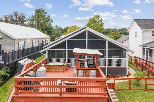 back of property featuring a wooden deck, a sunroom, and a hot tub