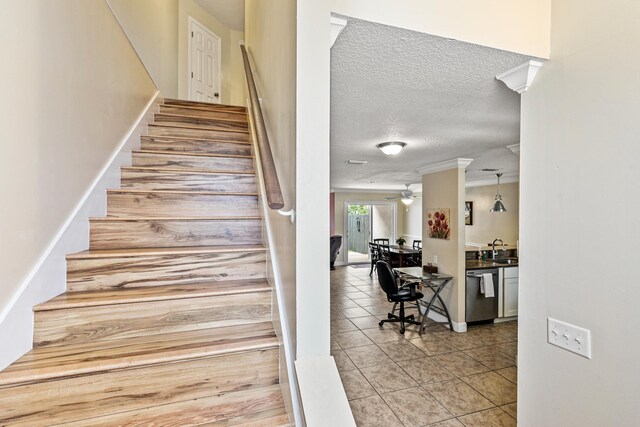 stairway featuring tile patterned floors, ceiling fan, sink, and a textured ceiling