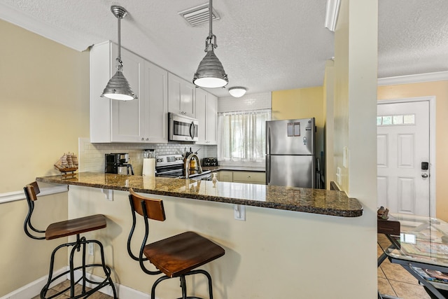 kitchen with kitchen peninsula, white cabinets, stainless steel appliances, and decorative light fixtures