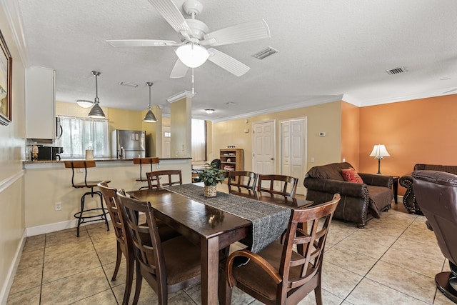 dining area with a textured ceiling, ceiling fan, ornamental molding, and light tile patterned flooring