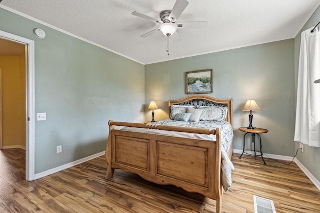 bedroom featuring ceiling fan, hardwood / wood-style floors, crown molding, and a textured ceiling