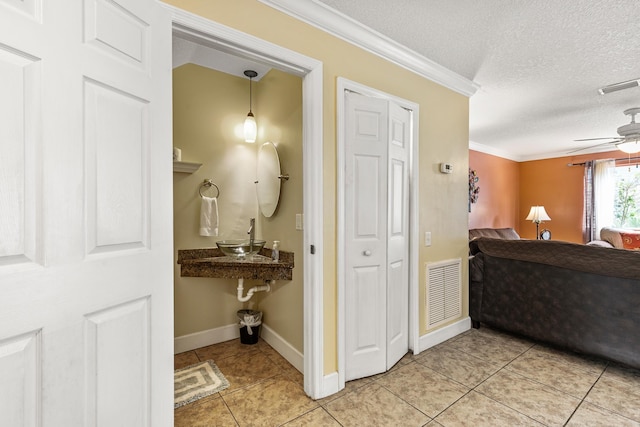 hallway with light tile patterned floors, a textured ceiling, and ornamental molding