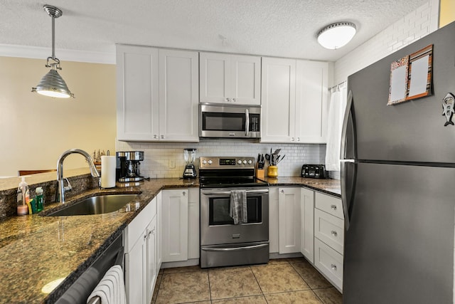 kitchen with white cabinets, sink, light tile patterned floors, appliances with stainless steel finishes, and decorative light fixtures