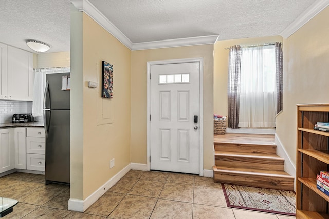 tiled entrance foyer featuring a textured ceiling and ornamental molding