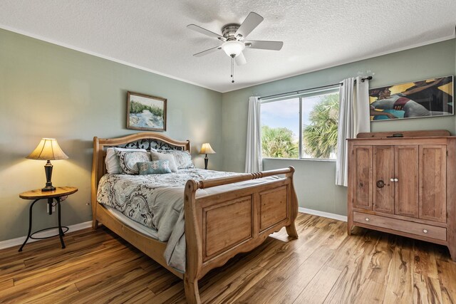 bedroom featuring hardwood / wood-style floors, a textured ceiling, ceiling fan, and crown molding