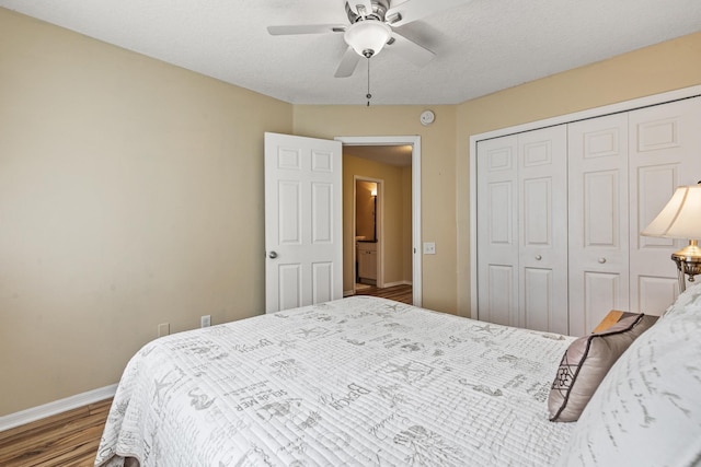 bedroom with ceiling fan, a closet, dark wood-type flooring, and a textured ceiling