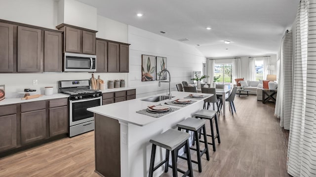 798 Grand Reserve Dr, Bunnell, FL 32110 - kitchen with stainless steel appliances, a sink, lofted ceiling, light wood-style floors, and a breakfast bar