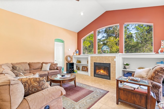 tiled living room with vaulted ceiling, a tiled fireplace, and built in shelves