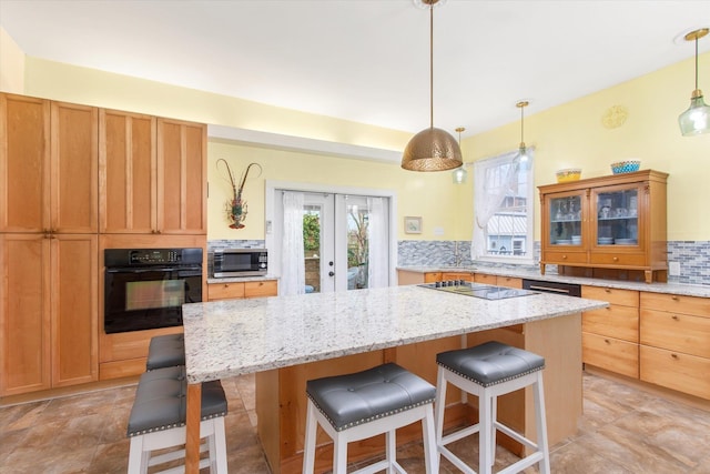 75 Osceola St, Saint Augustine, FL 32084 - kitchen featuring light stone counters, a kitchen island, tasteful backsplash, a kitchen breakfast bar, and black appliances