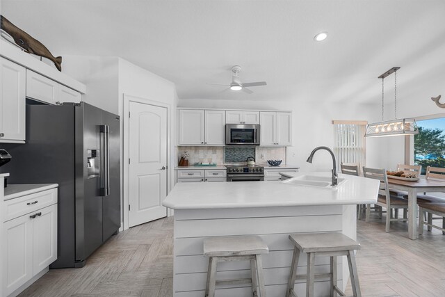 kitchen featuring light countertops, backsplash, appliances with stainless steel finishes, white cabinetry, and a sink