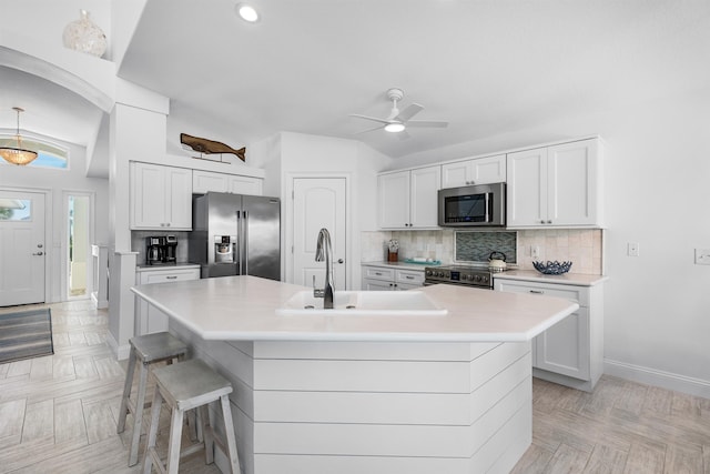 kitchen with a sink, light countertops, appliances with stainless steel finishes, tasteful backsplash, and an island with sink