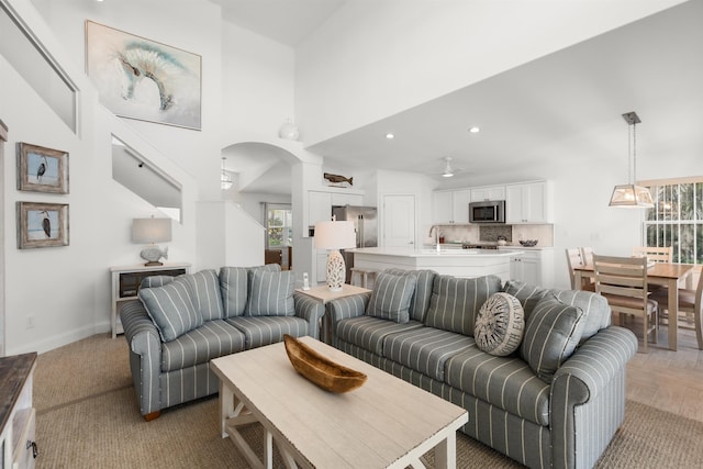 living room with a towering ceiling, baseboards, arched walkways, and recessed lighting