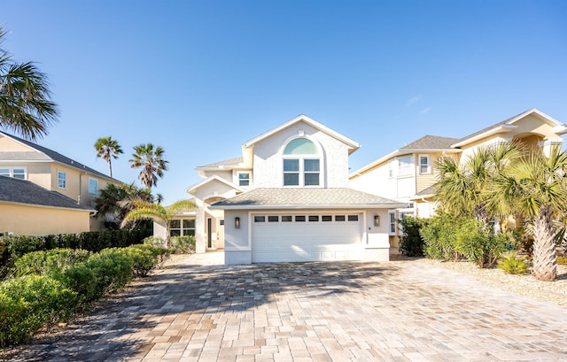 traditional-style home with decorative driveway, an attached garage, and stucco siding