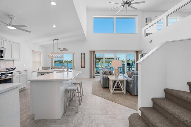 kitchen with white cabinets, ceiling fan, a breakfast bar area, open floor plan, and stainless steel appliances