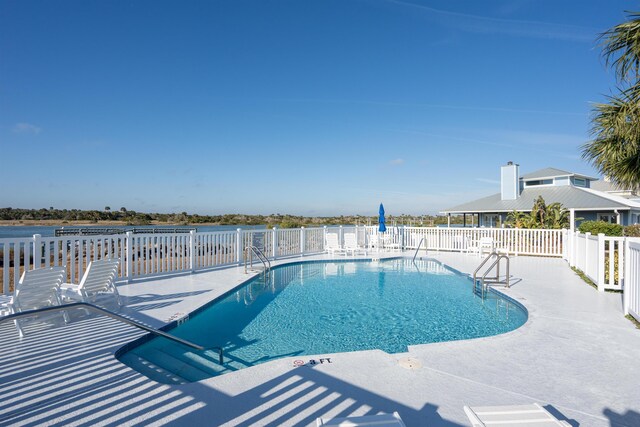 community pool with a patio area and fence