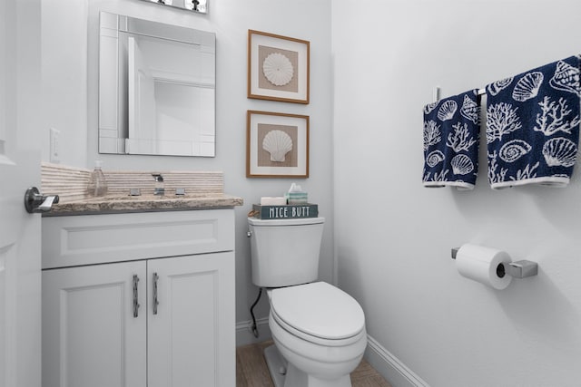 bathroom with baseboards, vanity, and toilet