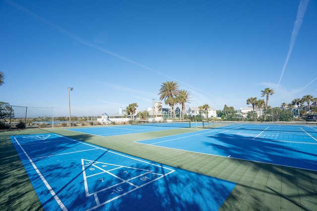 surrounding community with a tennis court, shuffleboard, and fence