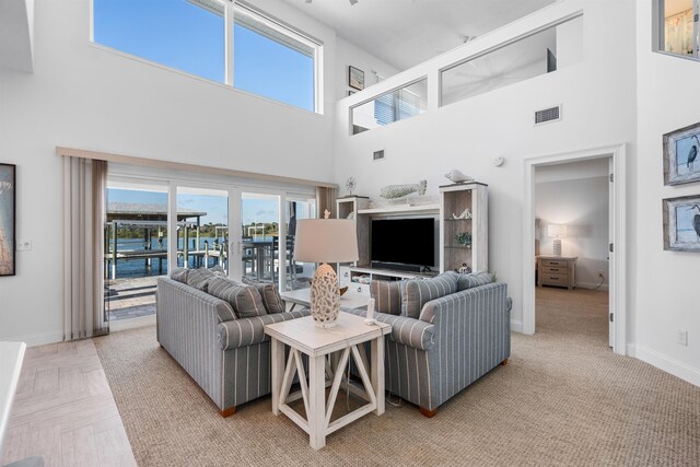 living area featuring baseboards, a high ceiling, and visible vents