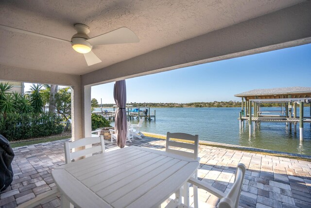 exterior space featuring a patio, outdoor dining space, a water view, and boat lift